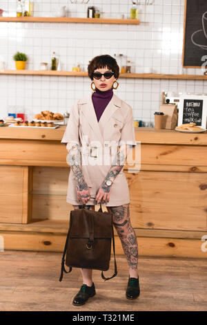 Attraktive, moderne Geschäftsfrau in Sonnenbrille an der Theke stehend in der Cafeteria Stockfoto