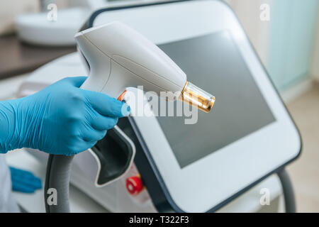 7/8-Ansicht der Kosmetiker in Gummihandschuhe Holding laser Gerät Stockfoto