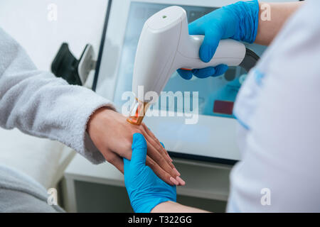 7/8-Ansicht der Kosmetologin tun Laser Haarentfernung Verfahren an Hand Stockfoto