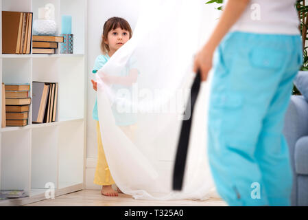 Elterliche Strafe. Kindesmissbrauch. Mama eine kleine Tochter mit einem Riemen bestrafen und setzt sie in eine Ecke. Nicht die Kinder schlagen, um Kinder zu schützen. Stockfoto