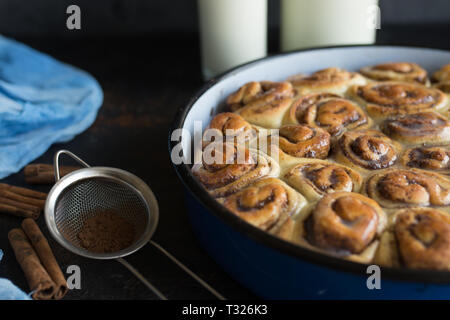 Cinnamon Roll Tarte mit Zuckersirup in vintage Backblech auf schwarzem Hintergrund Stockfoto
