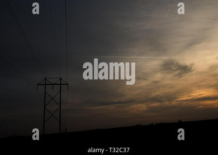 Hochspannungsleitung Turm durch einen Sonnenuntergang Silhouette, Polk County, Iowa Stockfoto