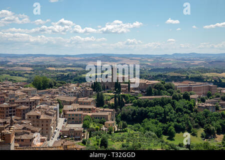 Panoramablick auf Siena Stadt mit historischen Gebäuden und weit weg die grünen Felder von Siena Dom (Duomo di Siena). Sommer sonnigen Tag und dramatische bl Stockfoto