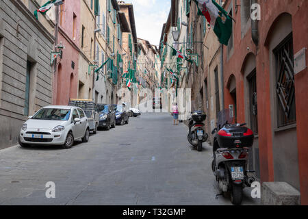 Siena, Italien - Juni 28, 2018: Wandern auf schmalen Straße in Siena Stadt mit historischen Gebäuden und Geschäften. Sommer Sonne und blauer Himmel Stockfoto