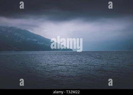 Blick auf den Thunersee und die Berge vom Schiff in der Stadt Spiez, Schweiz, Europa. Dramatische Moody blue clouds Szene Stockfoto