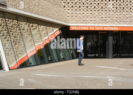 Ein junger Mann, der außerhalb der Tate Modern, London, England, Großbritannien, mit seinem Mobiltelefon telefoniert Stockfoto