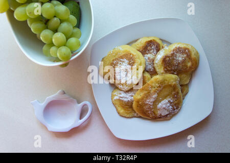 Traditionelle polnische Pfannkuchen auf einen Teller und grüne Trauben - Süße Pfannkuchen mit Puderzucker bestreut Stockfoto