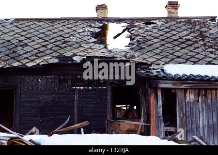 Ein altes Haus, das durch Feuer aus einer Naturkatastrophe oder die Fahrlässigkeit von Menschen zerstört wird. Spuren von Feuer sind sichtbar auf dem Haus. Stockfoto