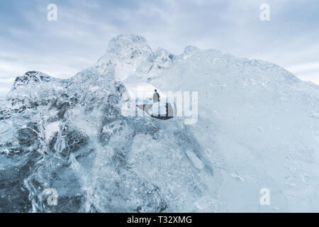 Auf der Suche durch die Bohrung in einem Eisberg gibt einen einzigartigen Blick auf eine Person alon auf Diamond Beach in Island. Stockfoto