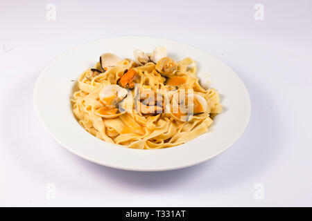 Nudelgericht mit Miesmuscheln und Venusmuscheln auf weißem Hintergrund Stockfoto