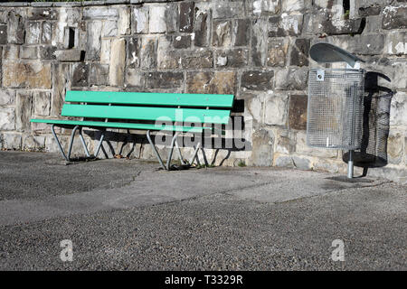 Eine grüne Bank aus Holz und Abfall können an einem sonnigen Frühlingstag in Nyon, Schweiz fotografiert. Auf diesem Foto sehen Sie auch Asphalt Gehweg. Stockfoto