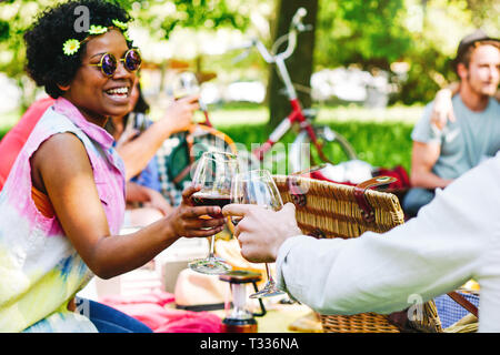 Junge Menschen, die ein wundervolles Picknick im Park genießen die freudigen Moment trinken und Essen - glückliche Freunde toasten Gläser Wein Stockfoto