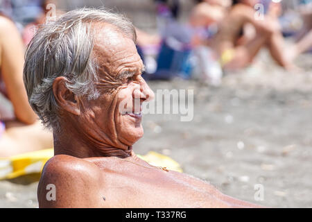 Toskana, Italien, 17. JULI 2018: Seitenansicht eines kontemplativen Casual älterer Menschen am Strand. Stockfoto