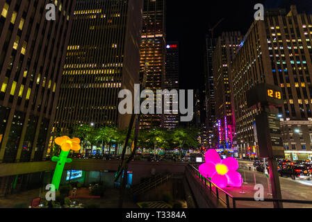 New York City, USA - Juli 30, 2018: 47-50 Straßen Rockefeller Center Station in der Nacht auf die Sixth Avenue (6. Avenue) mit riesigen bunten Plastikblumen Stockfoto