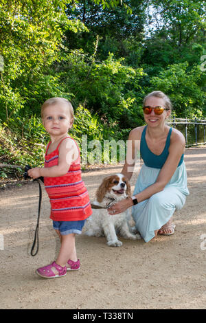 Mutter, Mädchen Kleinkinder- und Cavalier King Charles Spaniel, am Kellermeister Trail im Zilker Park in Austin, Texas, USA Stockfoto