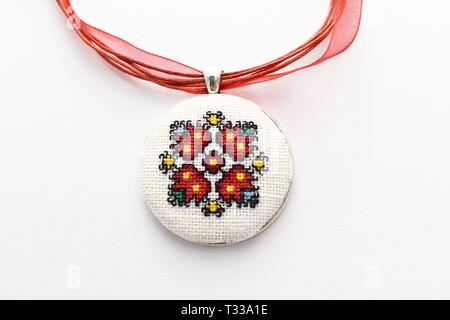 Handmade Cross Stitch Halskette rote Blume bestickt auf der weißen Leinwand Stockfoto