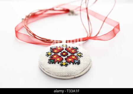 Handmade Cross Stitch Halskette rote Blume bestickt auf der weißen Leinwand Stockfoto