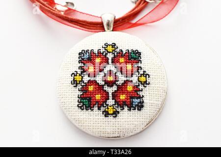 Handmade Cross Stitch Halskette rote Blume bestickt auf der weißen Leinwand Stockfoto