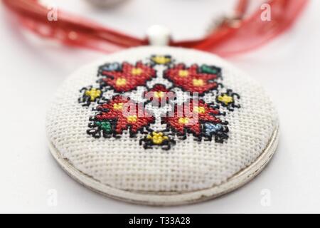 Handmade Cross Stitch Halskette rote Blume bestickt auf der weißen Leinwand Stockfoto