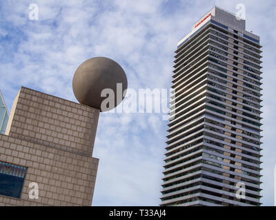 BARCELONA, SPANIEN - 14. MÄRZ 2019: Frank Gehrys Sphäre Skulptur vor dem Port Olímpic, neben Torre Mapfre Wolkenkratzer, diagonale Komposition Stockfoto