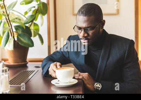 Junge hübsche dunkelhäutige Geschäftsmann Getränke Kaffee in einem Cafe Stockfoto