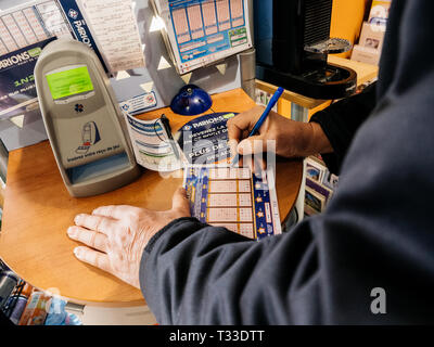 Paris, Frankreich - 29 Mar 2019: älterer Mann Kennzeichnung Zahlen auf Euromillions ticket in tabac Presse Kiosk in der Hoffnung, den großen Jackpot von 10000000 Millionen Euro zu gewinnen. Stockfoto