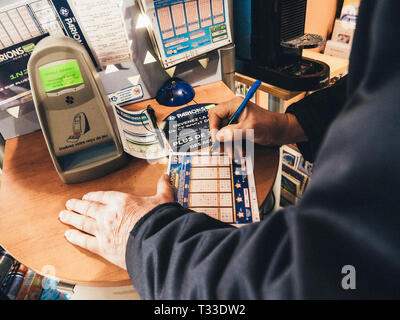 Paris, Frankreich - 29 Mar 2019: Älterer männlichen Händen Kennzeichnung Zahlen auf Euromillions ticket in tabac Presse Kiosk in der Hoffnung, den großen Jackpot von 10000000 Millionen Euro zu gewinnen. Stockfoto