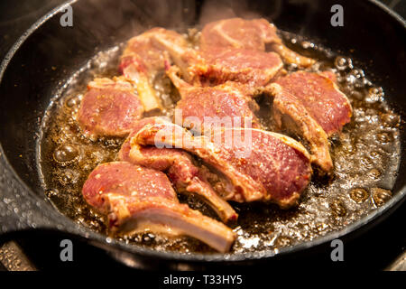 Kochen, Fleisch, Lamm Koteletts werden in einer Pfanne gebraten, Stockfoto