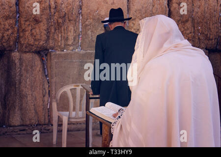 Religiöse orthodoxen Juden in den Vordergrund trägt einen Gebetsschal betet an der Klagemauer, Jerusalem, Israel drapiert. Männliche Figur in weiß Lesen der Heiligen Stockfoto