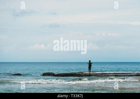 Junger Mann, die Bilder von das Meer stehen am Ufer. Skyline. blaues Meer, blauer Himmel mit Wolken. Stockfoto