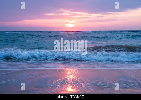 Schöne Aussicht auf das Meer mit kommenden Surf Wellen unsed Sonnenuntergang Himmel. Reflexion von Sonnenlicht in Wasser und Sand am Strand. Andaman und Nicobar Inseln, Indi Stockfoto