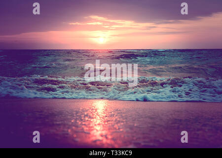 Reflexion von Sonnenlicht in Wasser und Sand am Strand. Rosa und Lila Strand Sonnenuntergang. Wellen in der Morgendämmerung. Andaman und Nicobar Inseln, Indien. Neil, Havelock Stockfoto