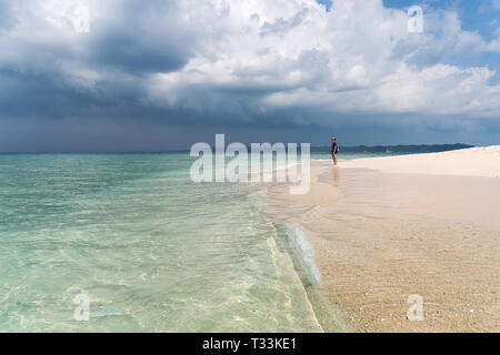 Paradise Beach Clean Blue Ocean mit weißem Sand. Ein junger Tourist steht auf dem weißen Sand auf einem sauberen Strand und in die Ferne schaut gegen die Clo Stockfoto