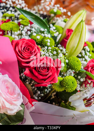 Strauß Blumen, Rosen und lirius, rote und grüne Zusammensetzung Stockfoto