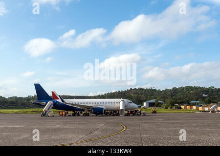 Passagierflugzeug steht auf der Landebahn des Flughafens auf dem Hintergrund einer kleinen Flughafen. Laden Gepäck entladen der Flugzeuge. Stockfoto