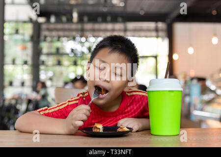 Happy Face Asian Boy genießen Sie Schokolade essen Waffel im Restaurant. Stockfoto
