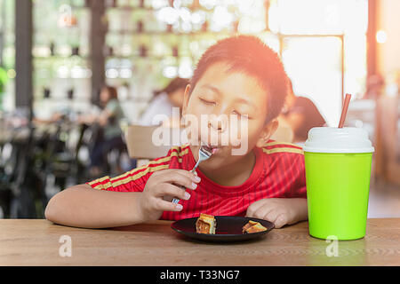 Happy Face Asian Boy genießen Sie Schokolade essen Waffel im Restaurant. Stockfoto