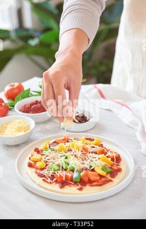 Baker's Hand Zutaten auf der Pizza Stockfoto