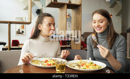 Zwei Frau Freunde zusammen Essen im Cafe und Reden, ihre Speisen genießen. Vorderansicht. Stockfoto