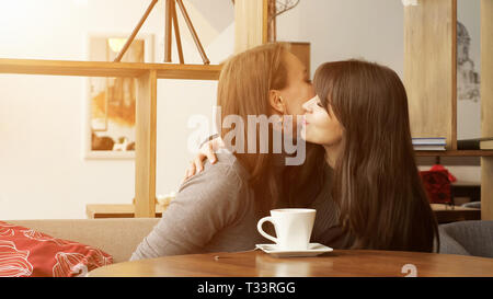 Zwei Freundinnen treffen sich im Cafe und Küssen, Sonnenlicht Stockfoto