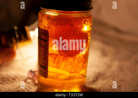 Natürlicher Honig Süßstoff in einem Glas mit goldgelben Beleuchtung Stockfoto