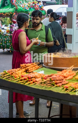 Ein junges asiatisches Paar, das Essen auf einem Markt probiert und probiert, der Straßennahrung in thailand, asien, verkauft. Stockfoto