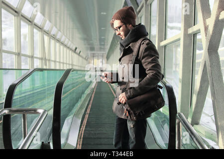 Junger Mann liest eine SMS während in der U-Bahn stehen Stockfoto