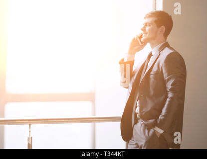Bis zu schließen. Geschäftsmann sprechen auf dem Smartphone beim Stehen in der Nähe ein Büro Fenster Stockfoto