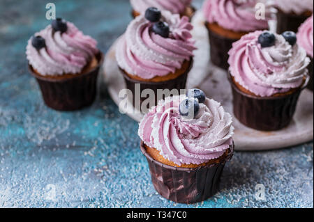 Vanille Cupcakes mit Heidelbeere Sahne und Beeren. Close-up. Selektiver Fokus Stockfoto