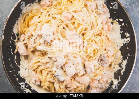 Italienische Pasta Linguine mit Lachs in Sahnesoße in der Pfanne. Ansicht von oben. Stockfoto