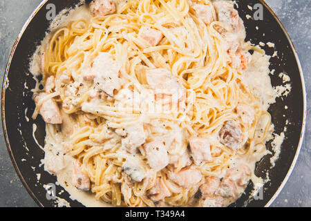 Italienische Pasta Linguine mit Lachs in Sahnesoße in der Pfanne. Ansicht von oben. Stockfoto