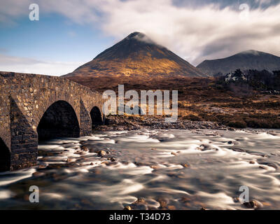 Kleine Brücke aus Stein bei Sligachan mit sgurr Mhairi im Hintergrund. Stockfoto