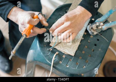 Männliche holding Lötkolben Werkzeug Reparatur, elektrische Kabel, Löten mit einem Lötkolben. Stockfoto