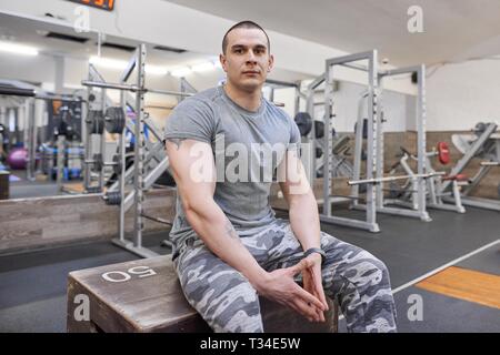 Porträt der jungen starken lächelnd muskulös lächelnden Mann in der Turnhalle Stockfoto